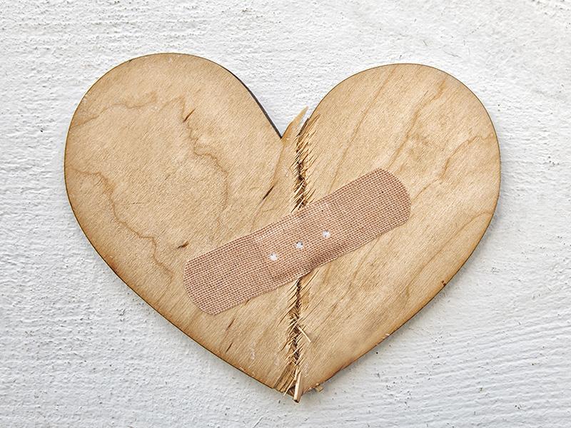 Broken wooden heart cutting board with bandaid