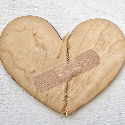 Broken wooden heart cutting board with bandaid